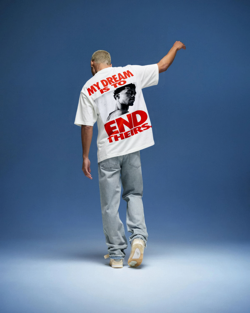 Person wearing a t-shirt with a graphic and text on the back, standing against a blue background